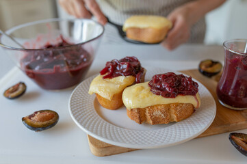 Delicious baked cheese sandwich with homemade plum chutney prepared by woman´s hands in the kitchen