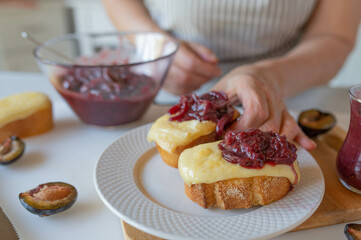 Delicious baked cheese sandwich with homemade plum chutney prepared by woman´s hands in the kitchen