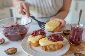 Delicious baked cheese sandwich with homemade plum chutney prepared by woman´s hands in the kitchen