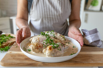 Homemade food with a delicious fresh cooked dinner with chicken roulades in a tasty cream sauce served by woman´s hands in the kitchen
