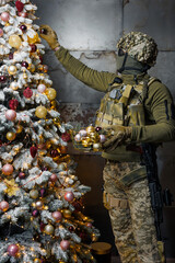 a soldier decorates a Christmas tree. a man in a military uniform decorates a Christmas tree