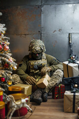 a soldier unwraps a gift near the Christmas tree. military Christmas 