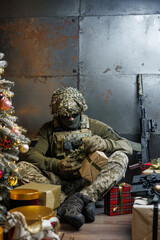 a soldier unwraps a gift near the Christmas tree