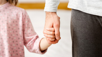 Father giving hand to his little daughter, close up, supporting, care, parenthood concept