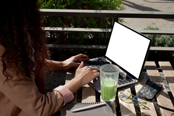 Woman working on a laptop at a summer terrace. Remote learning on a sunny terrace with a laptop....