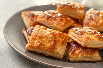 Puff cookies square with sugar in a plate. Delicious homemade cakes closeup