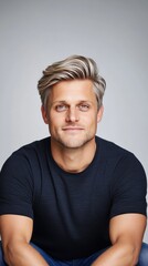 Obraz premium This striking visual captures a handsome man wearing a black t-shirt, posing against a gray background with sharp focus and professional color grading