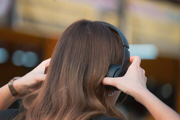 Fototapeta premium Young woman wearing black headphones listening to relaxing music after work.