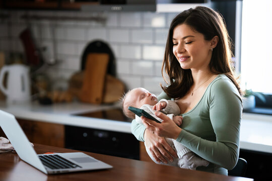 Stay at home mom working remotely on laptop while taking care of her baby. Global work on computer