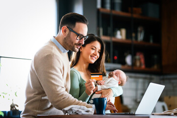 Cheerful young family with a baby child enjoying online purchasing on the internet at home