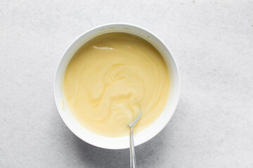 Overhead view of nigerian akamu being made in a white bowl, pap akamu or ogi in a white bowl, top...