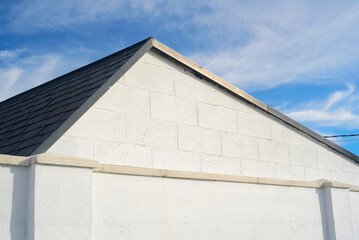 Fachada blanca triangular de bloques de hormigón, tejado y cielo