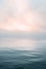 Obraz premium Serene Seascape at Dawn: A minimalist vista of a tranquil ocean, bathed in the soft, ethereal glow of sunrise, evokes a sense of peace and calm. The horizon blends seamlessly with the sky.