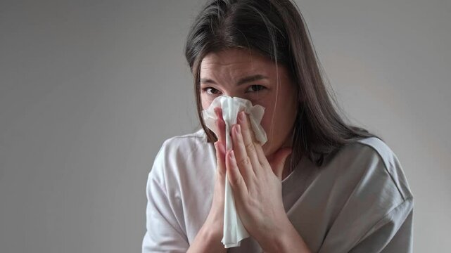 Woman sneezing while covering her nose with a tissue, showcasing an allergic reaction.
