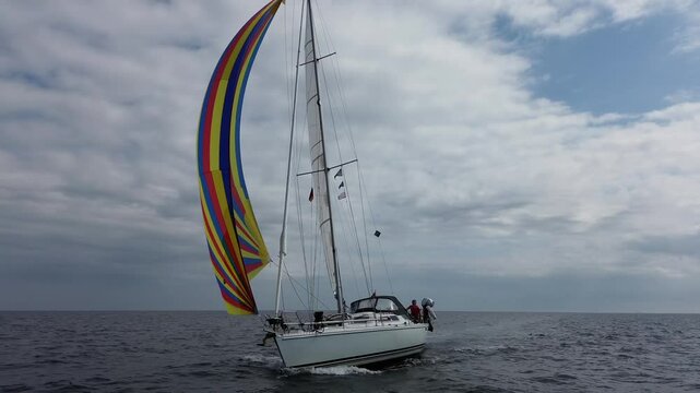 forward aerial drone 4K film of sailboat yacht with colcorful spinaker sail sailing on sea ocean water with Dutch holland flag