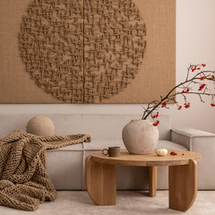 Interior design of living room interior with mock up poster, beige sofa, modern armchair, braided plaid, books, rowan in vase, pouf, lamp, bowl, rug and personal accessories. Home decor. Template.