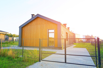 Obraz premium Barn House with green lawn. Barnhouse building in forest. Modern Family house on sunset. Cottage Scandi Barn home in suburb. Barndominium. Sustainable house in rural. Modern house with euro fence.