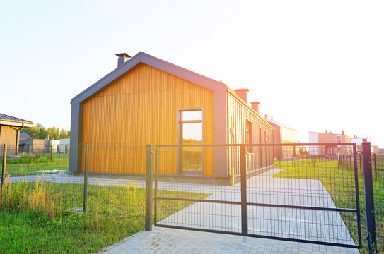 Barn House with green lawn. Barnhouse building in forest. Modern Family house on sunset. Cottage Scandi Barn home in suburb. Barndominium. Sustainable house in rural. Modern house with euro fence.