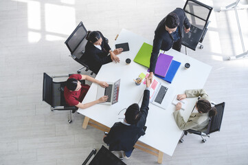 Top view of business partners shaking hands over the table after concluding a business agreement in...