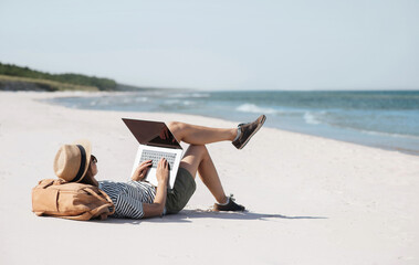 Young woman using laptop computer on beach, freelancer girl working remote, Freelance work, online...