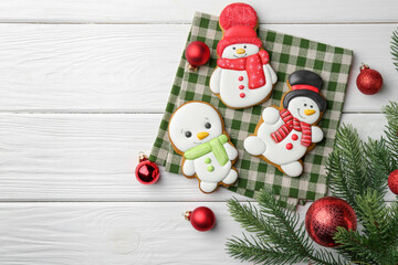 Delicious cookies in shape of snowmen and Christmas decor on white wooden table, flat lay. Space for text
