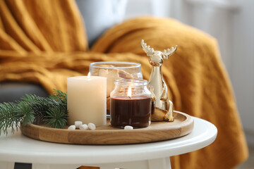 Burning candles, fir branches and decorative deer on coffee table indoors. Christmas atmosphere