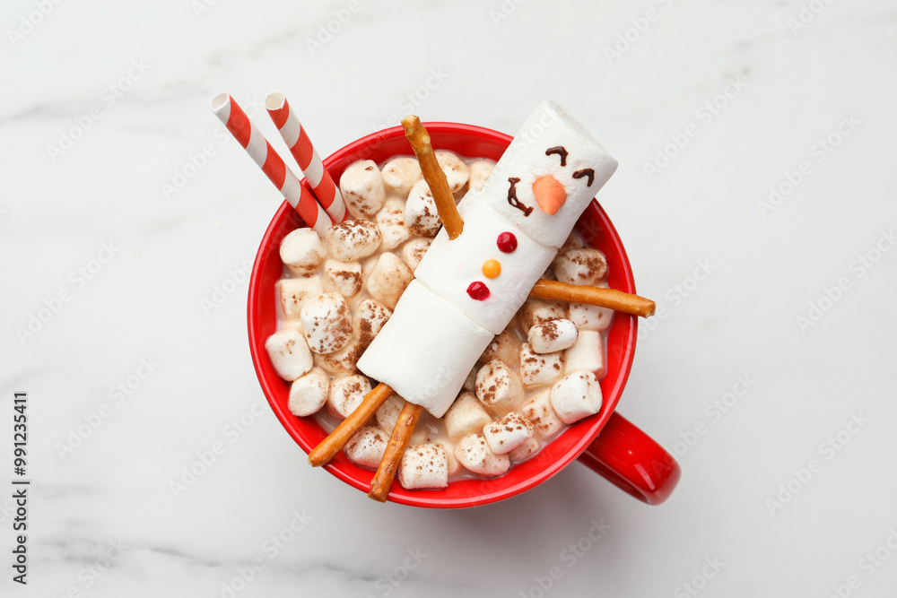 Wall mural Funny snowman made with marshmallows in cup of hot drink on white table, top view