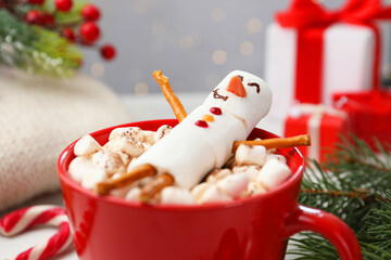Funny snowman made with marshmallows in cup of hot drink and Christmas decor, closeup