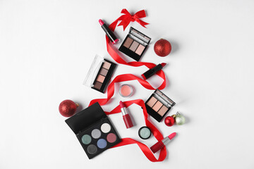 Christmas tree shape made with makeup products and decor on white background