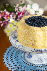 Homemade birthday cake called Apfelmus decorated with blueberries on porcelain plate on blue lace napkin