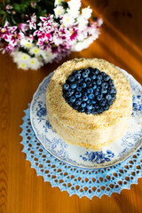 Homemade birthday cake called Apfelmus decorated with blueberries on porcelain plate on blue lace napkin