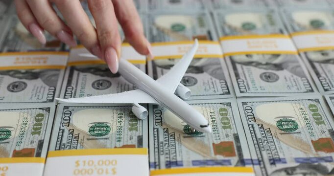 Model airplane flies over a stack of US hundred dollar bills