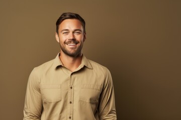Obraz premium Portrait of a glad man in his 30s sporting a breathable hiking shirt while standing against soft brown background