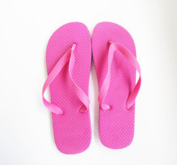 A pair of pink flip-flops with textured soles and simple straps, laid flat on a white surface,...