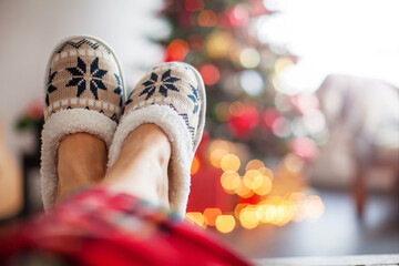 Legs in slippers on Christmas tree background