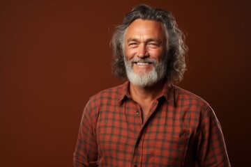 Obraz premium Portrait of a happy man in his 50s wearing a comfy flannel shirt on soft brown background