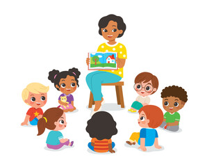 Kindergarten teacher reading and telling a story to children group showing book spread picture. Teacher talks to student sit on floor in circle and listen to her.