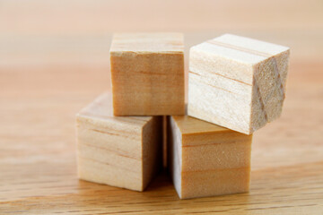 Four wooden cubes on a surface of the same material