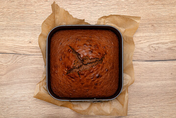 Baked cocoa cake lying on a square baking tray.