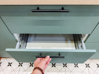 In a wellequipped kitchen, a person meticulously opens a drawer, revealing a diverse array of...