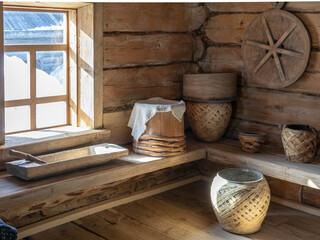 The sun's rays through the window fall on ceramic pots in an old wooden house. Kitchen utensils in an old wooden house. Antique tableware and household items in a rustic log house.