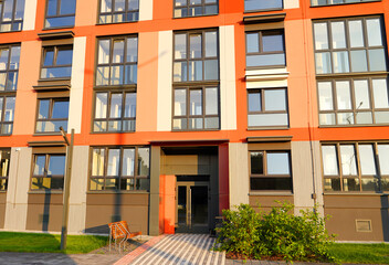 Entrance to Condo house complex. Eco-friendly residential building with green courtyard, Lawn. Facade of New residential building. Entrance to staircase in apartment block. City Street Pedestrian path