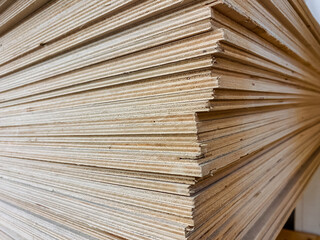 This closeup image shows a neatly stacked pile of plywood sheets, highlighting the intricate textures and patterns of this essential material used in construction and design