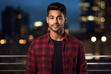 Fototapeta premium Portrait of a tender indian man in his 20s wearing a comfy flannel shirt over modern cityscape background