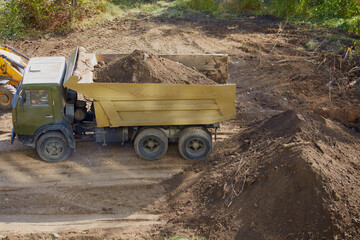 Obraz premium Dump truck with soil parked on a construction site. The process of excavation at the initial stages of construction.