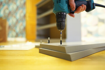 Furniture assembly use Cordless combi drill. Fiberboard for furniture assembly in house flat. Wooden panel made of fiberboard. Medium Density Fiberboard (MDF). Woodworking, furniture assembly