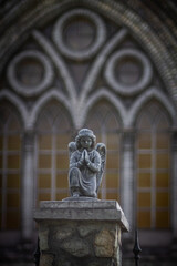 Obraz premium Against a background of arched church windows, statue of a winged angel praying. Color vertical photograph from bottom to top. 