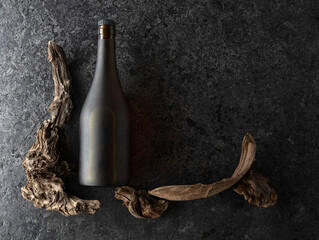 Vintage bottle of brandy and old snags on a black stone background.