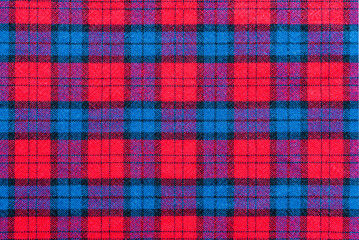 The texture of linen fabric in a large cage of blue, red. Scottish tailoring material. Checkered fabric