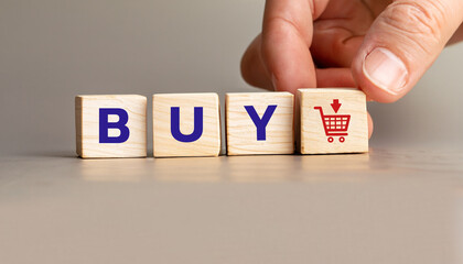 Hand Placing Wooden Blocks Spelling buy with Shopping Cart Icon, Stock Image for E-commerce, Online Shopping, Business Marketing, Product Promotions, and Digital Retail Concepts.